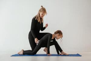 Teaching, how to sit on, twine. Mother, and little daughter are in fitness clothes on yoga mat photo