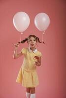 Showing, tongue, playful, with balloons. Cute little girl is against pink background photo