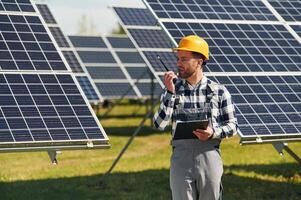 Communication by using walkie talkie. Engineer with photovoltaic solar panels outdoors at daytime photo
