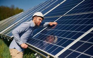 In formal clothes. Engineer with photovoltaic,, solar panels outdoors at daytime photo