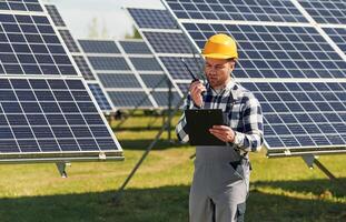 Talking by, radio. Engineer with,,, photovoltaic solar panels outdoors at daytime photo