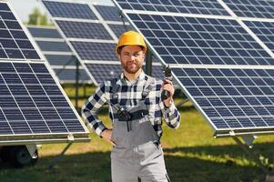 Drill, in ,hand. Engineer with photovoltaic solar panels outdoors at daytime photo