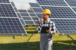 Communication, by using walkie talkie. Engineer with photovoltaic solar panels outdoors at daytime photo