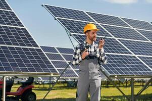 Talking, by, radio. Engineer with photovoltaic solar panels outdoors at daytime photo