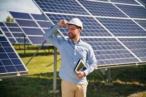 Digital ,tablet,, in hand. Engineer with photovoltaic solar panels outdoors at daytime photo
