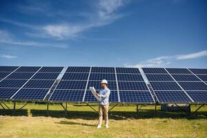 Distant, view.... Engineer with photovoltaic solar panels outdoors at daytime photo