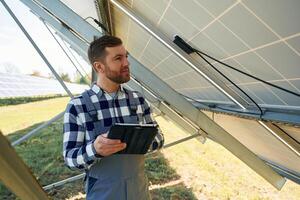 Under the photovoltaic solar panel, and, with digital tablet. Engineer outdoors at daytime photo