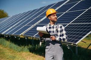 On, the, field with notepad in hands. Engineer with photovoltaic solar panels outdoors at daytime photo