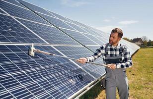 Process of cleaning the surface. Engineer with photovoltaic solar panels outdoors at daytime photo