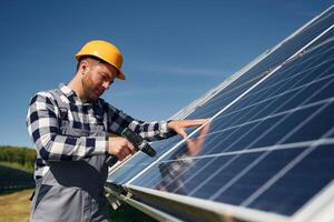 Almost, done, installation by using, drill. Engineer with photovoltaic solar panels outdoors at daytime photo