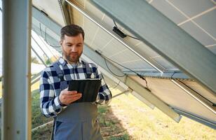 Under the photovoltaic solar panel and ,with digital tablet. Engineer outdoors at daytime photo