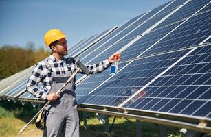 Procedure of cleaning the surface. Engineer with photovoltaic solar panels outdoors at daytime photo