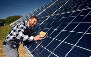 Surface must me clean... Engineer with photovoltaic solar panels outdoors at daytime photo