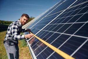 Measuring, the, width,, by tape. Engineer with photovoltaic solar panels outdoors at daytime photo