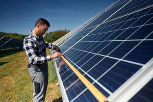 Measuring the ,width by tape. Engineer, with photovoltaic solar panels outdoors at daytime photo