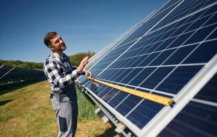 Measuring the ,width by tape. Engineer with photovoltaic solar panels outdoors at daytime photo