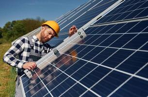 Using the, leveler tool. Engineer, with photovoltaic solar panels outdoors at daytime photo