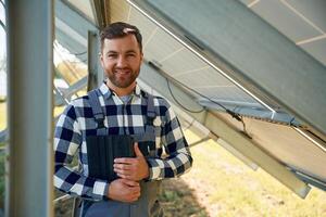 Under the photovoltaic solar panel and ,,with digital tablet. Engineer outdoors at daytime photo