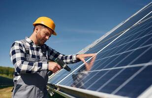 Almost done,,, installation by using drill. Engineer with photovoltaic solar panels outdoors at daytime photo