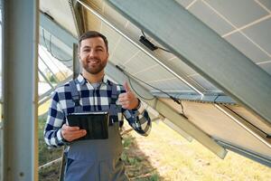 Under, the photovoltaic solar panel and with digital tablet. Engineer outdoors at daytime photo
