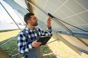 Under the ,photovoltaic solar panel and with digital tablet. Engineer outdoors at daytime photo