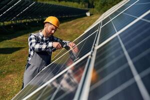 Drill ,in hand. Engineer with photovoltaic solar panels outdoors at daytime photo