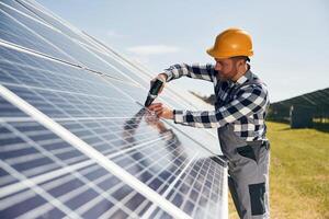 Installation process,,, with drill. Engineer with photovoltaic solar panels outdoors at daytime photo