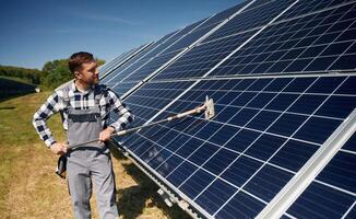 Process of cleaning, the, surface. Engineer with photovoltaic solar panels outdoors at daytime photo