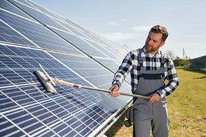 Process of cleaning ,the,, surface. Engineer with photovoltaic solar panels outdoors at daytime photo