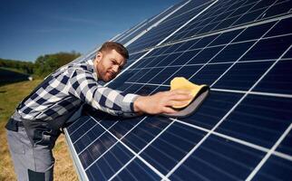 Surface, must ,,me clean. Engineer with photovoltaic solar panels outdoors at daytime photo