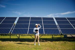 Digital ,tablet in hand. Engineer, with photovoltaic solar panels outdoors at daytime photo