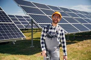 Ready to work, with drill. Engineer with photovoltaic solar panels outdoors at daytime photo