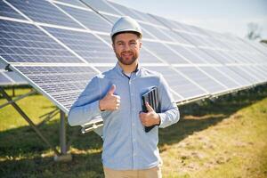 Digital, tablet ,in hand. Engineer with photovoltaic solar panels outdoors at daytime photo