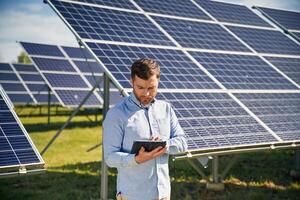 Digital tablet ,in ,,hand. Engineer with photovoltaic solar panels outdoors at daytime photo