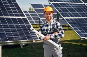 Portrait, holding, leveler tool. Engineer with photovoltaic solar panels outdoors at daytime photo