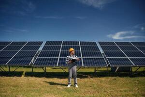 Black, notepad, in, hands. Engineer with photovoltaic solar panels outdoors at daytime photo