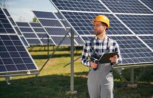 On the, field, with notepad in hands. Engineer with photovoltaic solar panels outdoors at daytime photo
