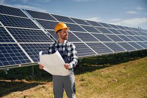grande ,papel ,con plan, lectura. ingeniero con fotovoltaica solar paneles al aire libre a tiempo de día foto