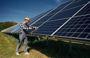 Almost done,, installation by using drill. Engineer with photovoltaic solar panels outdoors at daytime photo