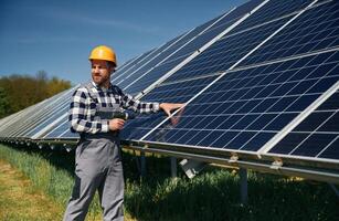 Almos,t done, installation by using drill. Engineer with photovoltaic solar panels outdoors at daytime photo