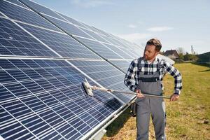 Process of cleaning ,the surface. Engineer with photovoltaic solar panels outdoors at daytime photo
