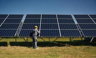 Rear,, view, the maintenance. Engineer with photovoltaic solar panels outdoors at daytime photo