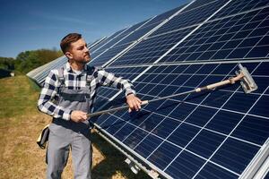 Mop, in, hands. Cleans the surface. Engineer with photovoltaic solar panels outdoors at daytime photo