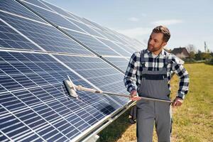 Process ,of cleaning the surface. Engineer with photovoltaic solar panels outdoors at daytime photo