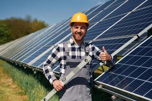 Portrait, holding ,leveler tool. Engineer with photovoltaic solar panels outdoors at daytime photo