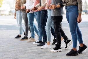 International group of young activists holding hands and moving towards copy space. Unrecognizable protestors making strike on the street, showing their unity and strength, cropped photo