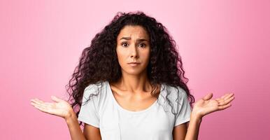 I Don't Know. Concerned young woman shrugging shoulders with spreaded hands, unsure brunette lady looking at camera with misunderstanding, standing over purple studio background, copy space photo