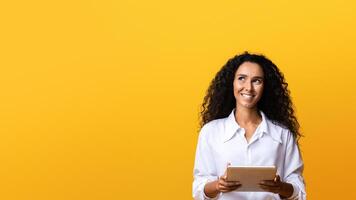 Portrait Of Pensive Brunette Woman With Digital Tablet Computer, Looking At Copy Space, Standing Over Yellow Background, Thinking About Something, Having Online Offer, Browsing Internet, Panorama photo