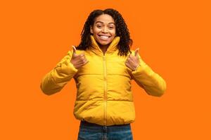 I Like It. Black Girl Gesturing Thumbs Up With Both Hands Posing On Yellow Studio Background photo