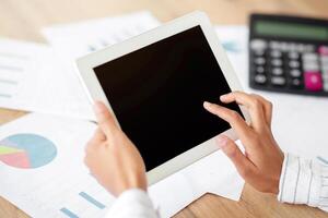 Cropped view of black business lady using tablet computer with blank screen at table with documents, mockup for app or website design. Unrecognizable female CEO working on touch pad, space for text photo